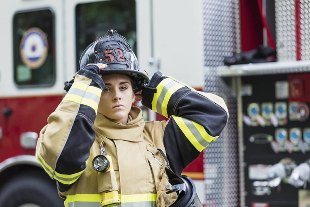 身穿消防服的女性消防员站在消防引擎旁20多岁的年轻女子有严肃表达方式